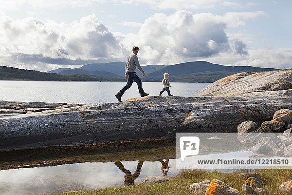 Man and son walking on fjord rock formation  Aure  More og Romsdal  Norway