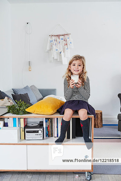 Young girl sitting in living room  holding glass of milk