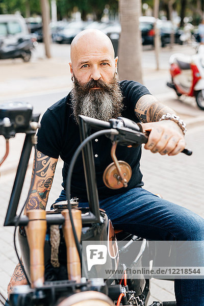 Portrait of mature male hipster astride motorcycle in parking lot