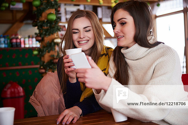 Junge Frauen lächeln über Textnachrichten auf Mobiltelefonen