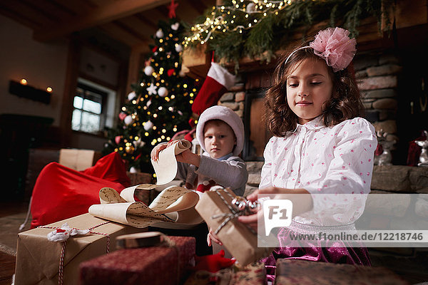 Junge Mädchen und Jungen sortieren Weihnachtsgeschenke  rollende Liste der Jungen