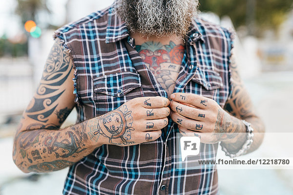 Tattooed male hipster fastening shirt buttons  cropped