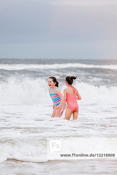 Two girls standing in ocean waves  Dauphin Island  Alabama  USA