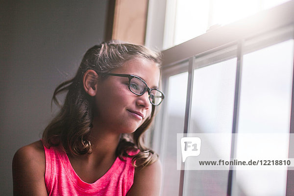 Young girl  wearing glasses  looking out of window