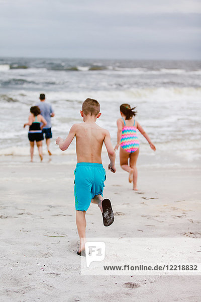 Mann und Kinder rennen vom Strand aufs Meer zu  Rückansicht  Dauphin Island  Alabama  USA