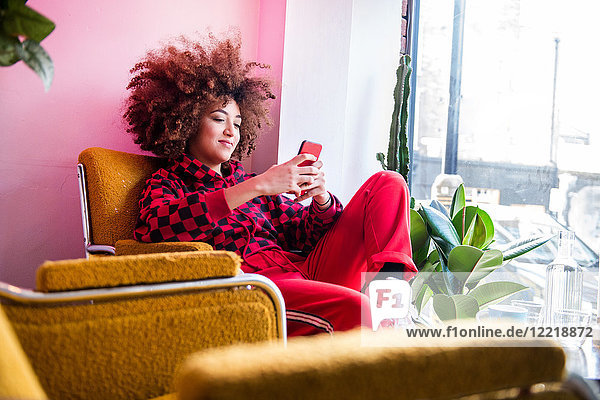 Young woman sitting indoors  using smartphone