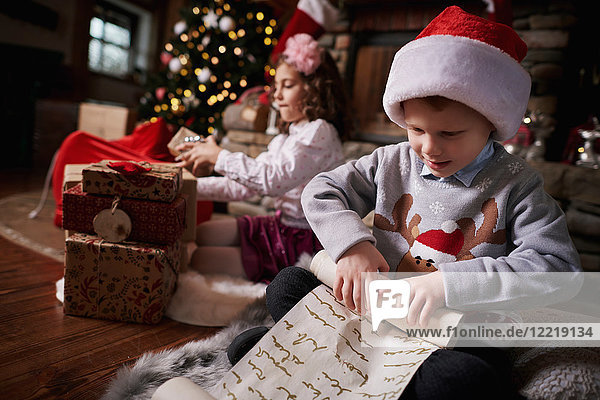 Junge Mädchen und Jungen sortieren Weihnachtsgeschenke  rollende Liste der Jungen