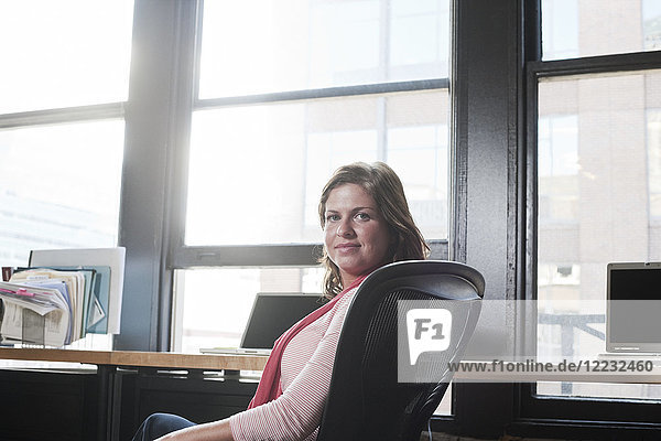 View of a Caucasian woman at her desk in a creative office.
