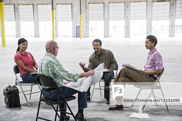 Multi-racial team of people going over plans for a new warehouse interior.