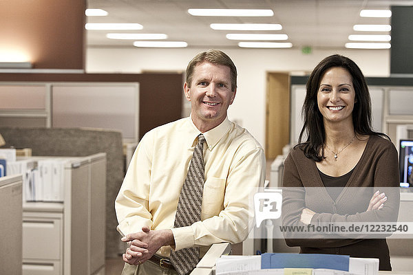 Caucasian man and woman executives in cubicle area of new office space