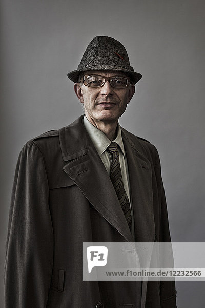 Studioporträt eines kaukasischen männlichen Schauspielers mit Hut und Mantel.
