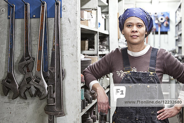 Schwarze Fabrikarbeiterin in Overalls in einer großen Blechfabrik.