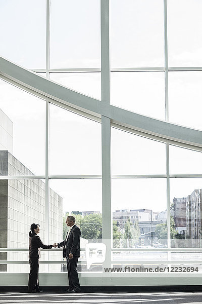 Businessman and woman meeting in a large glass covered walkway
