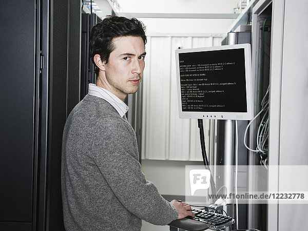 Kaukasischer männlicher Techniker der auf Computerservern in einer Computerserverfarm arbeitet.
