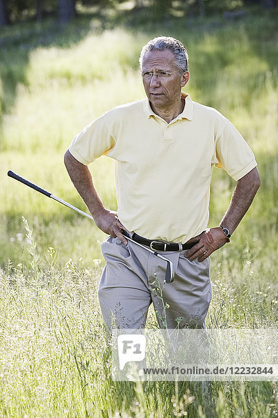 Älterer Golfspieler auf der Suche nach einem Golfball  der auf dem Golfplatz in ein schweres Rough geflogen ist.