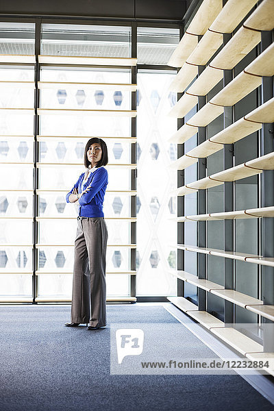 Asiatische Geschäftsfrau in der Lobby eines großen Bürogebäudes.