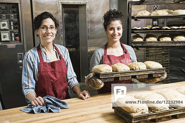 Female bakers working at a bakery with loaves of bread.
