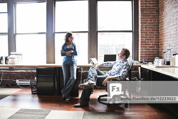 Caucasian woman and man meeting to discuss an issue at a creative office workstation.