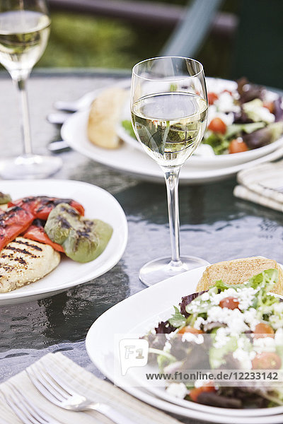 Closeup of a glass of wine and a healthy meal of salad on a table.