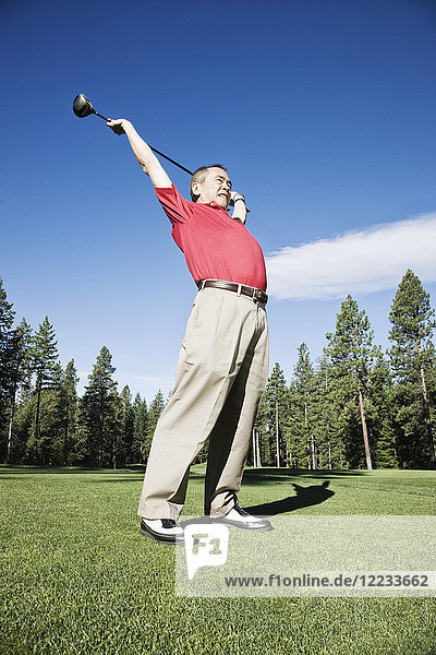 Senior golfer stretching with a golf club prior to playing a round of golf.
