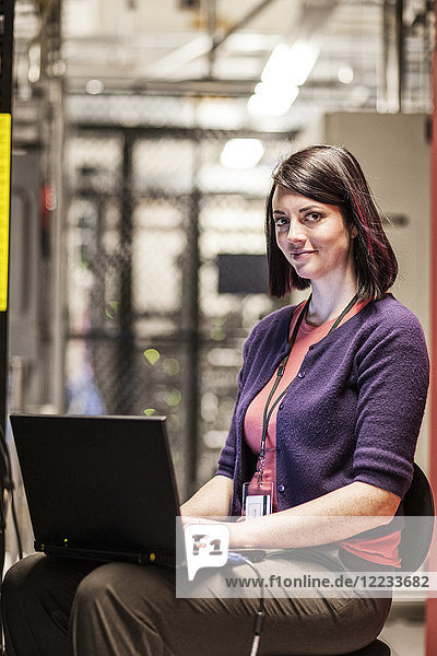 Caucasians woman technician working in a large computer server farm.