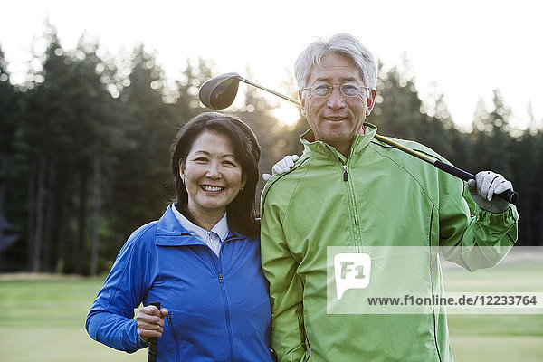 A young Asian senior couple playing golf.