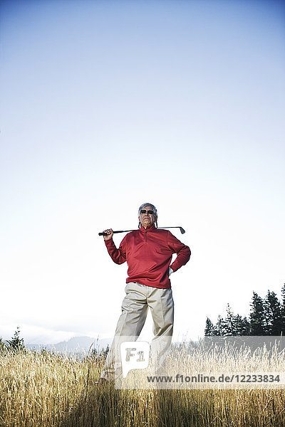 Älterer Golfer  der im schweren Rough steht und über seinen nächsten Schlag nachdenkt.