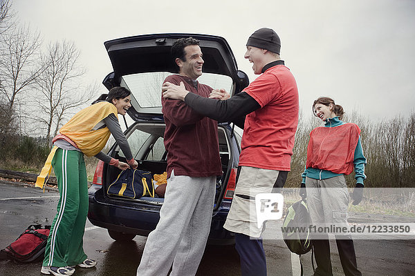 Gruppe von Freunden  die vor einem American Flag Football-Spiel Ausrüstung aus einem Auto entladen.