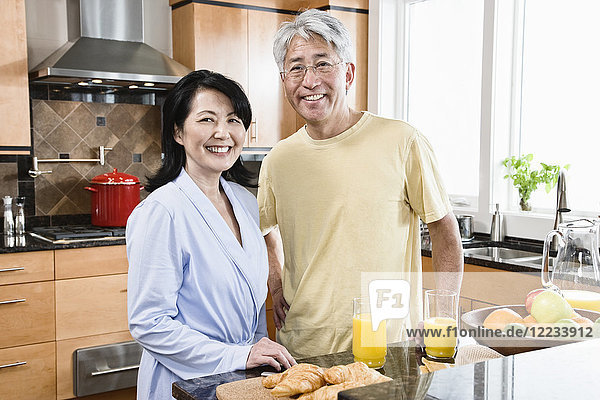 Asian man and woman in their new kitchen for breakfast.
