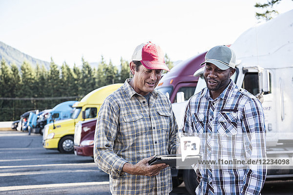 Ein kaukasischer Mann und ein schwarzer Lkw-Fahrer fahren gemeinsam auf einem Truckstop-Parkplatz.