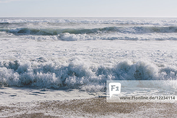 Meereslandschaft mit brechenden Wellen am Sandstrand.