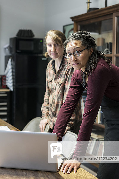 Zwei Frauen versammelten sich im Bürobereich einer Metallwerkstatt um einen Tisch und betrachteten einen Laptop.