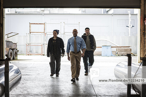 Workers and management person walking through a door into a sheet metal factory.