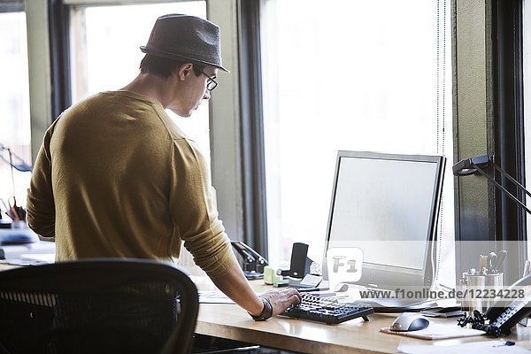 Hispanic male at his office workstation in a creative office.
