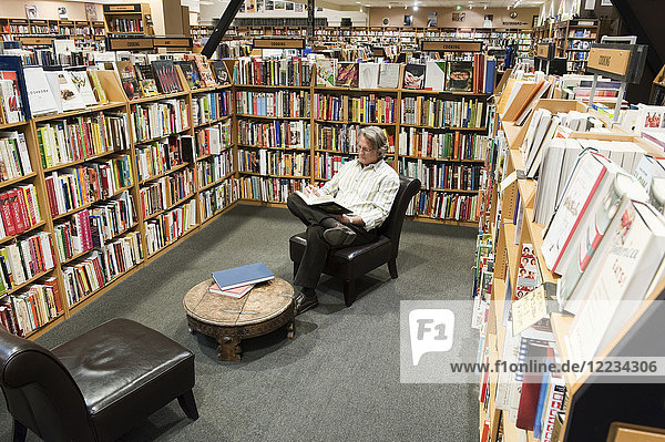 Caucasian male browsing through books in a large bookstore.