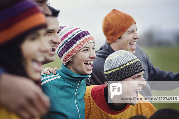 Group of men and women friends cheering at an informal sporting event in winter.