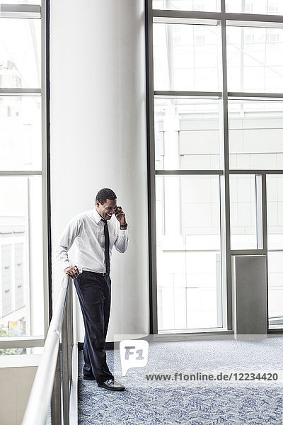 Black businessman on the phone in an office lobby.