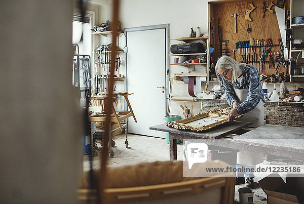 Senior female owner working on carved product at workshop