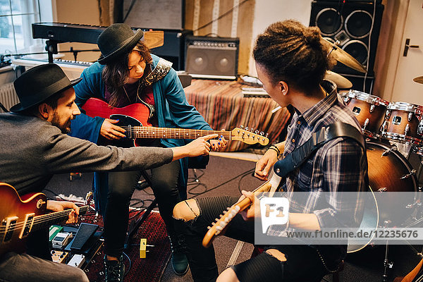 Mann der eine Freundin unterrichtet während er im Aufnahmestudio Gitarre spielt.