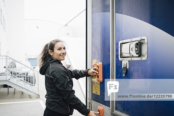 Lächelnde Frau drückt Knöpfe am Lieferwagen