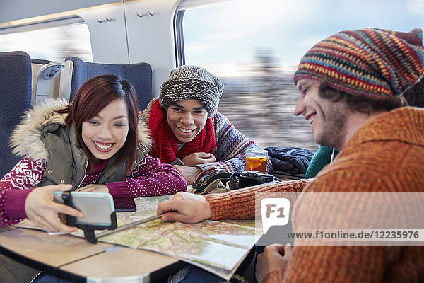 Junge Freunde mit Landkarte  die Selfie mit Selfie-Stick im Personenzug nehmen