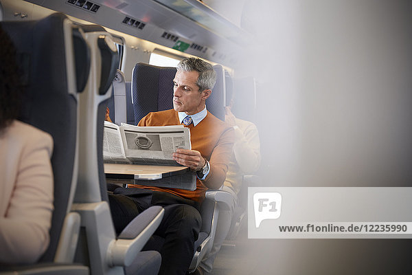 Businessman reading newspaper on passenger train