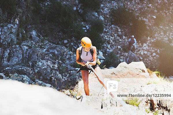 Female rock climber rappelling rock