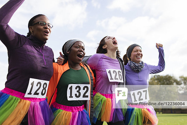 Enthusiastic female runner friends in tutus cheering at charity run