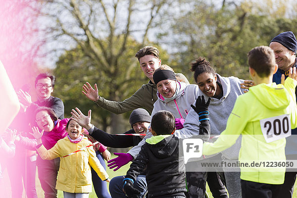 Spectators high-fiving runners at charity run in park