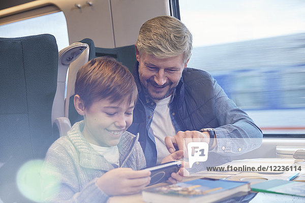 Vater und Sohn mit Smartphone im Personenzug