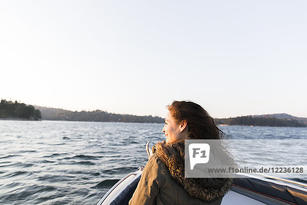 Lächelnde Frau beim Bootfahren auf dem sonnigen,  ruhigen See