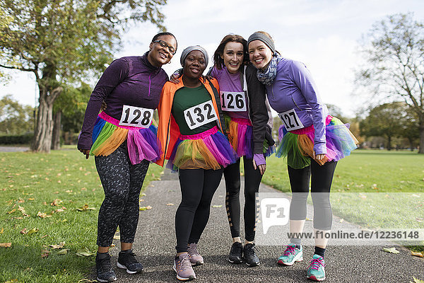 Portrait smiling  confident female runners in tutus at charity run in park