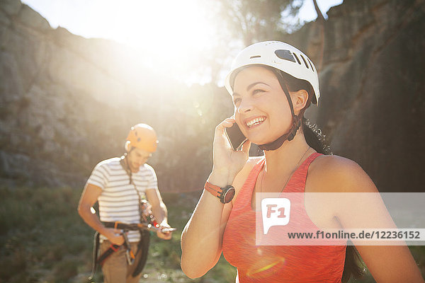 Smiling female rock climber talking on smart phone