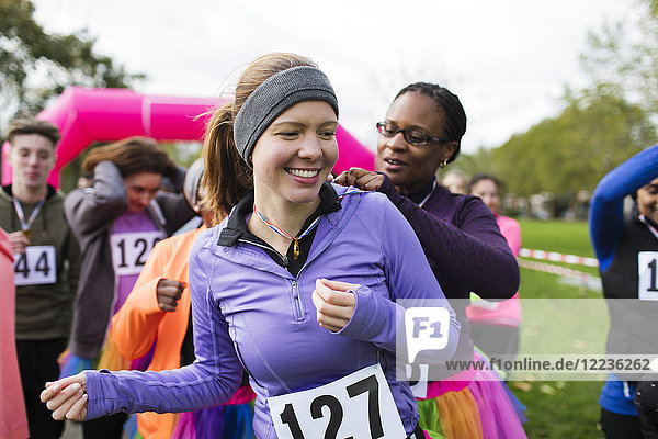 Woman pinning marathon bib on friend at charity run in park